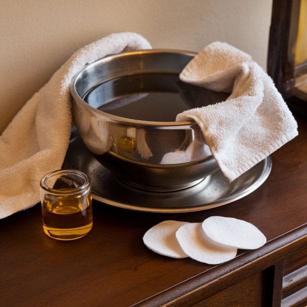 Tools for removing eyelash extensions at home: hot water bowl, towel, coconut oil, cotton pads.