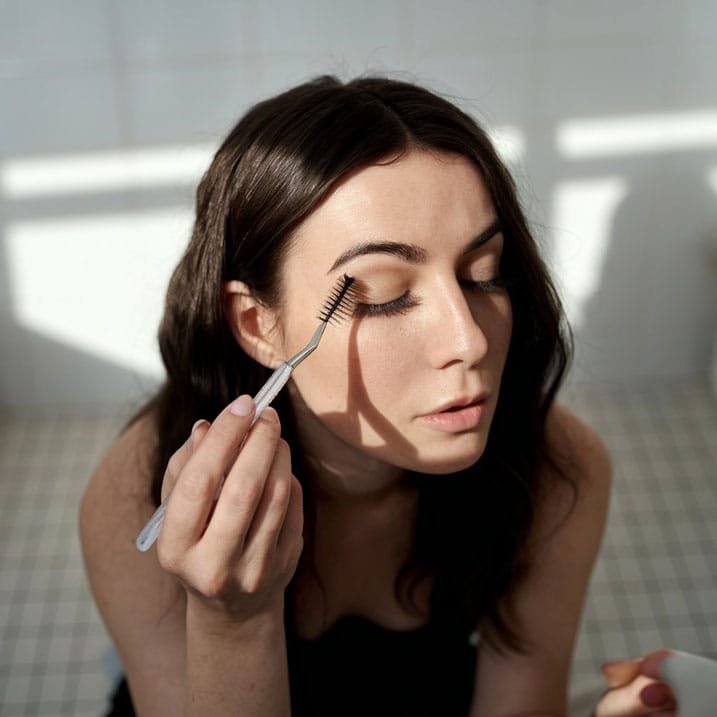 Brushing natural eyelashes with a spoolie brush for healthy growth.